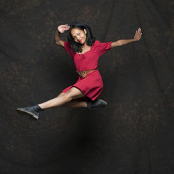 Full length of woman dancing on stage against black background