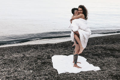 A couple in love spend the night at the sea, kissing and hugging on the beach covered with a blanket