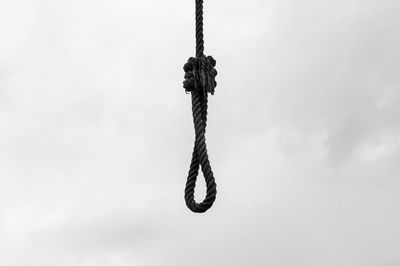 Close-up of chain tied up rope against sky