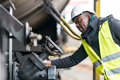 African american mechanic wearing safety equipment checking and inspecting gear train