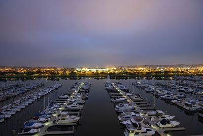 Aerial view of illuminated city buildings by sea against sky