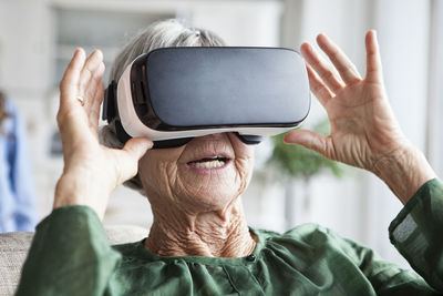 Senior woman using virtual reality glasses at home