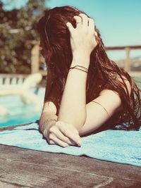 Woman with hand in hair leaning on table