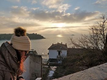Man looking at riverbank against sky during sunset