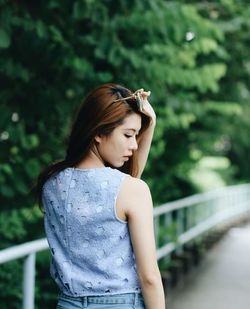 Young woman looking away while standing against railing