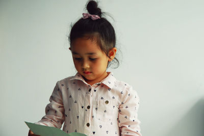 Innocent girl holding paper against wall