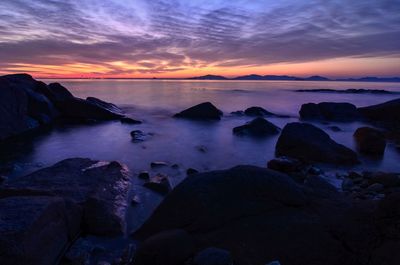 Scenic view of sea against dramatic sky during sunset