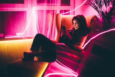 Rear view of woman sitting on bed at home