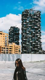 People walking in city against cloudy sky