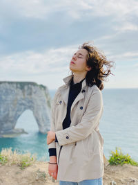 Young woman looking at sea shore against sky