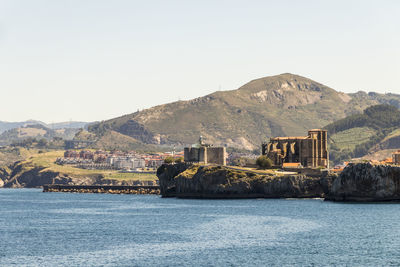 Sea by buildings against clear sky