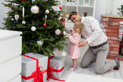 Portrait of woman holding christmas tree at home