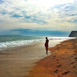 Full length of man walking on beach against sky