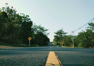 Road by trees against clear sky