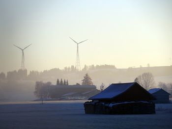 Wind turbines on snow covered landscape against sky