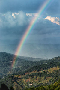 Scenic view of rainbow over mountain against sky