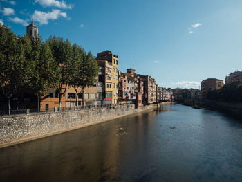 Buildings by river in town against sky