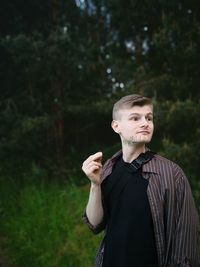 Portrait of young man standing against trees