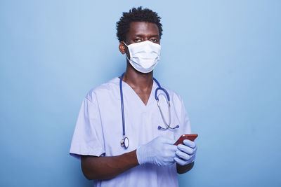 Portrait of young woman standing against blue background