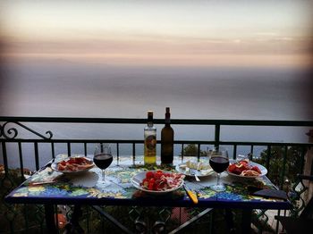 Food on table against sea during sunset