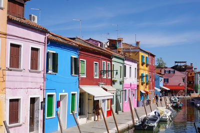 Houses by canal against sky in city