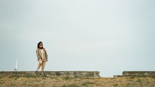 Woman standing on field against clear sky