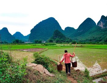 Rear view of man standing on mountain against sky