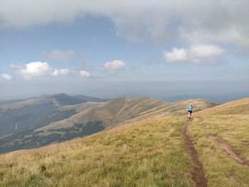 Rear view of man standing on mountain against sky