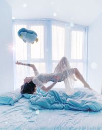 Side view of woman levitating with toy over bed at home