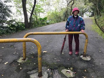 Full length of senior woman standing by barricade on road