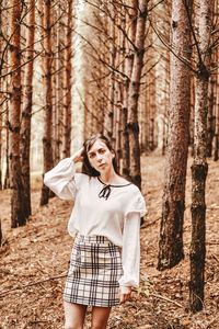 Portrait of young woman standing on tree trunk in forest