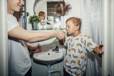 Boy brushing teeth in bathroom sink