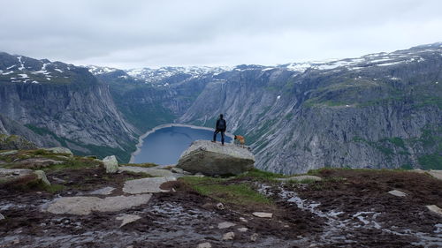 Rear view of man standing on rock against sky