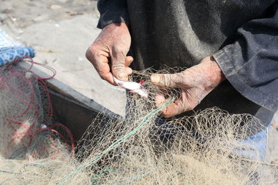 Midsection of man removing fish from net