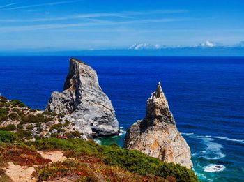 Rock formations in sea against blue sky