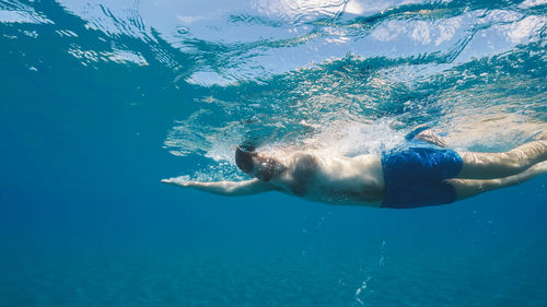 Boy swims freestyle in the open ocean.