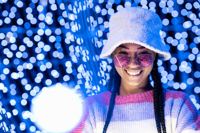 Joyful woman of color with a white beanie braided hairstyle and pink glasses enjoying the christmas 