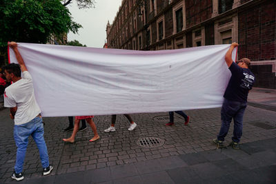 Rear view of people standing on footpath in city