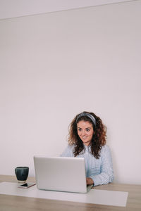 Portrait of young woman using phone while sitting on table