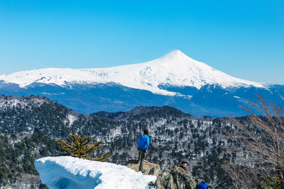 Rear view of snowcapped mountain against blue sky