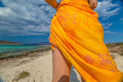 Low section of woman standing on beach against sky