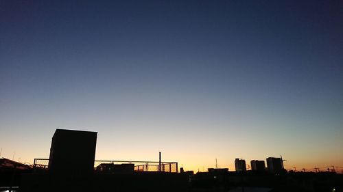 Silhouette buildings against clear sky at sunset