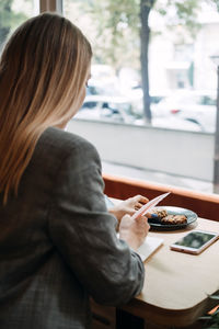 Midsection of woman using mobile phone while sitting on table