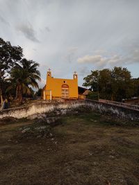 House by palm trees on field against sky