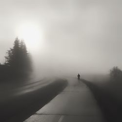 Rear view of silhouette person walking on road in winter