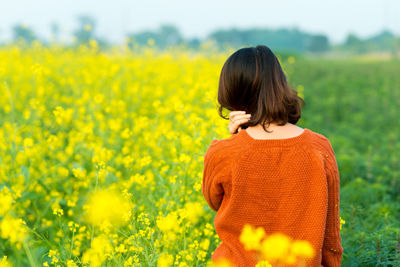 Rear view of young woman standing in field