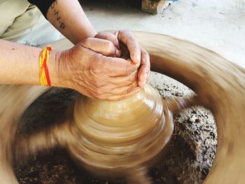 Midsection of potter shaping earthenware on pottery wheel