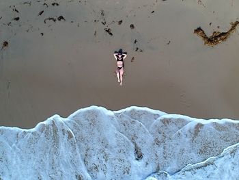Aerial view of woman relaxing on sea shore at beach