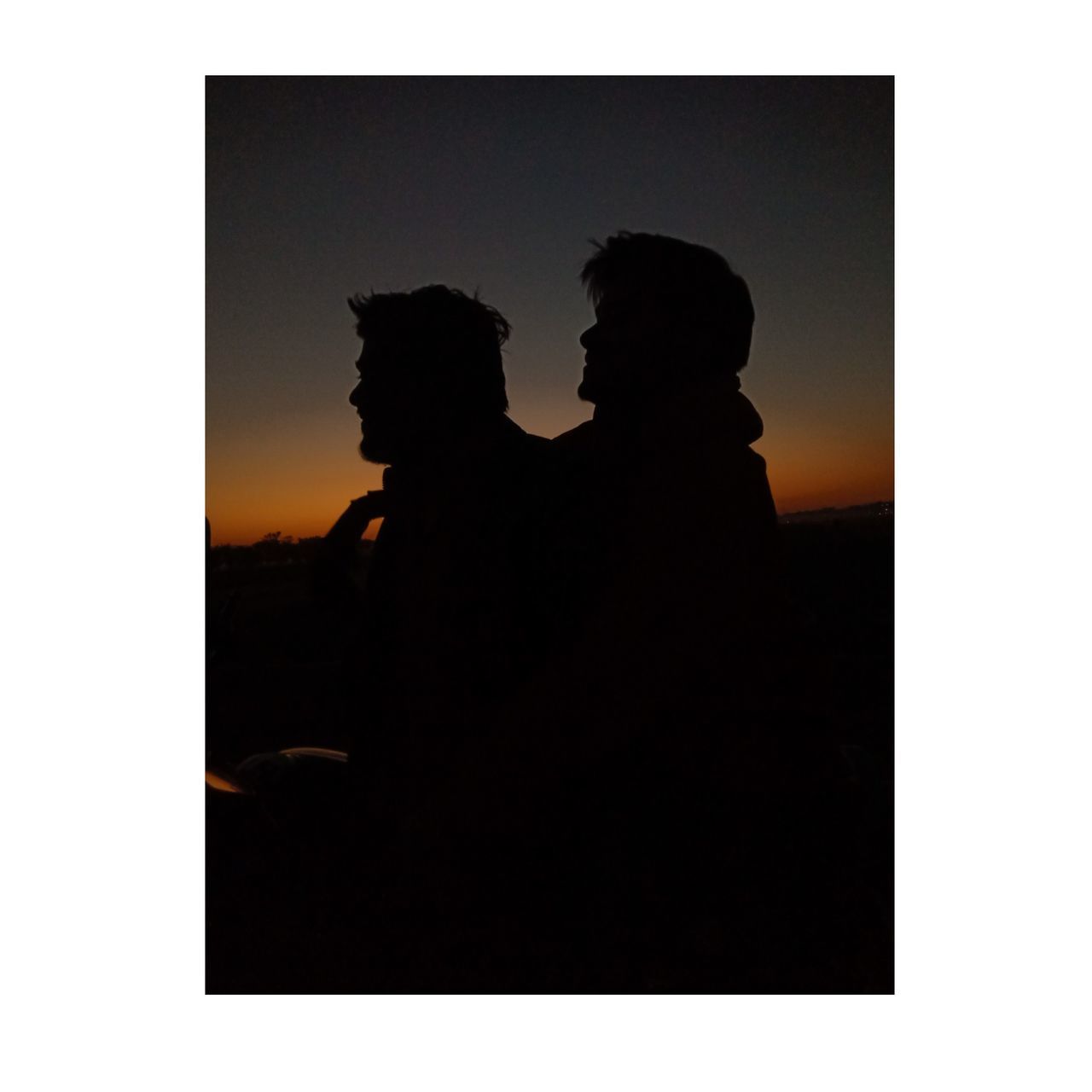 SILHOUETTE MAN AND WOMAN STANDING AGAINST WALL AT SUNSET