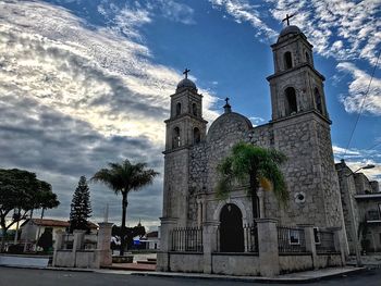 Low angle view of bell tower against cloudy sky